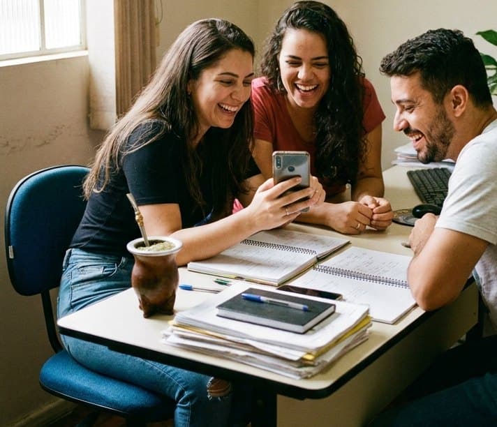 Equipe comercial reunida rindo enquanto olha uma conversa no celular